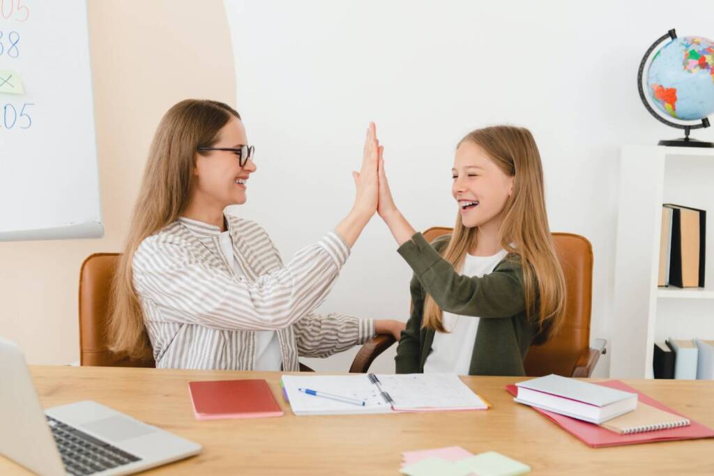 Teacher nanny helping daughter schoolgirl with homework, test, giving high five at homeschool.